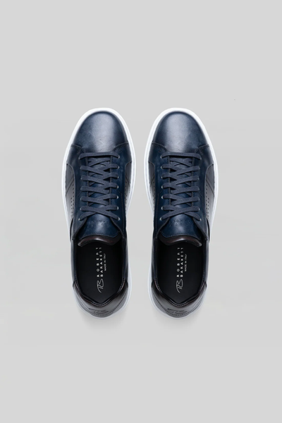 The Robert Barakett Dion Leather Sneaker is a premium men's dress sneaker in navy Italian calfskin with white soles, shown from above on a light grey background.