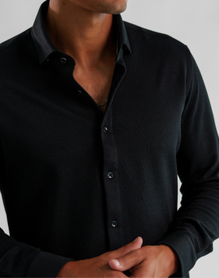 A man wearing a black Stone Rose ORIGIN - Long Sleeve Tech Pique Shirt with a collar.