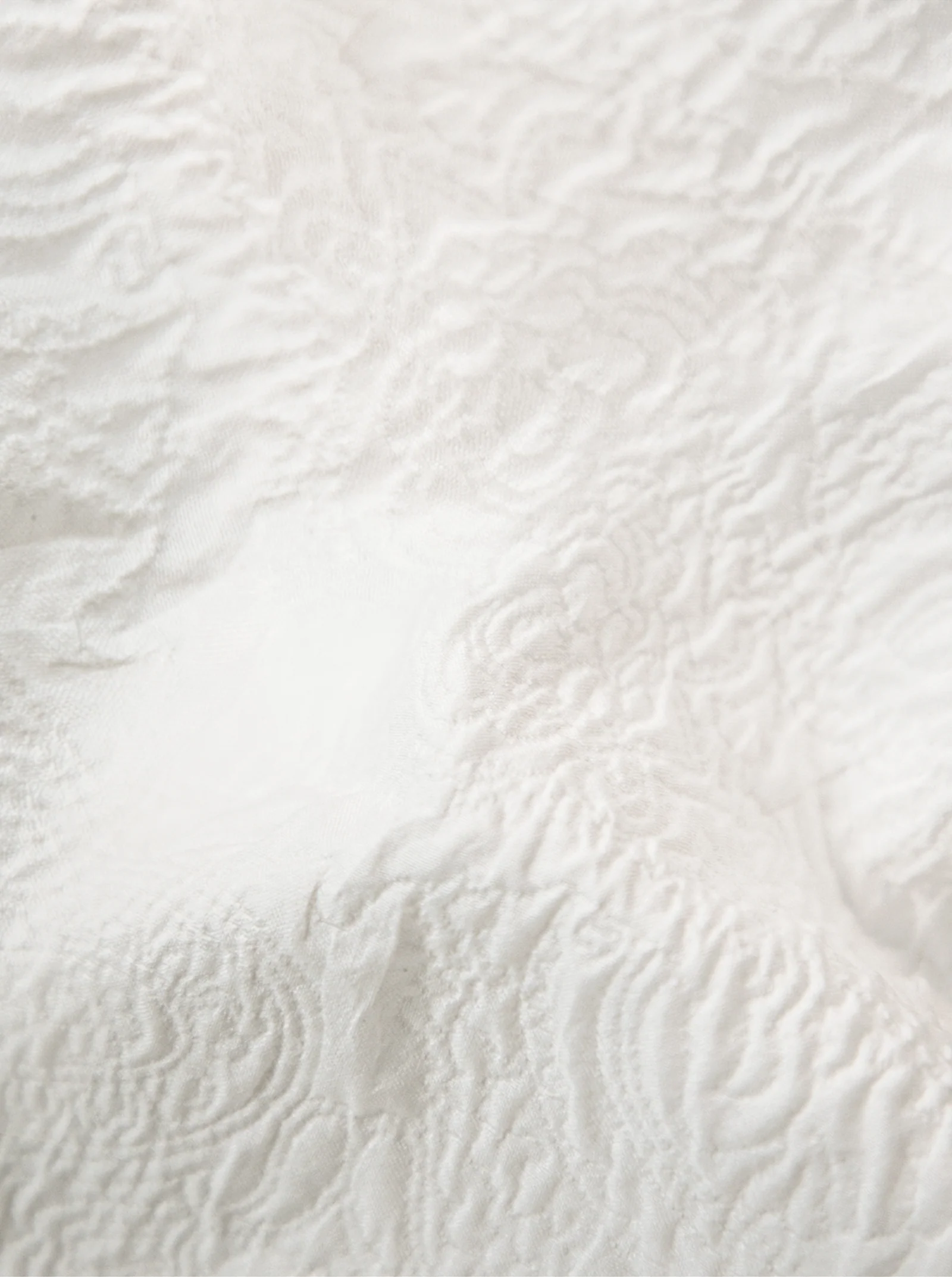 Close-up of the textured white fabric with a wavy, embossed pattern, echoing the intricate detail of the Robert Graham Devonshire Woven Shirt by Robert Graham.