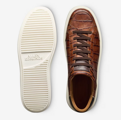 Top and bottom view of the Allen Edmonds Oliver Sneaker, featuring premium leather with a crocodile pattern, dark brown laces, and a white rubber sole embossed with the Allen Edmonds logo—a stylish and comfortable travel shoe.