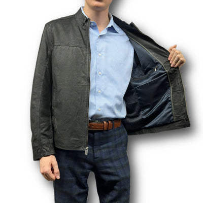 A person wearing a light blue dress shirt and dark plaid pants opens a Missani Vintage Leather Jacket 392794 to show its inner lining and interior pocket.