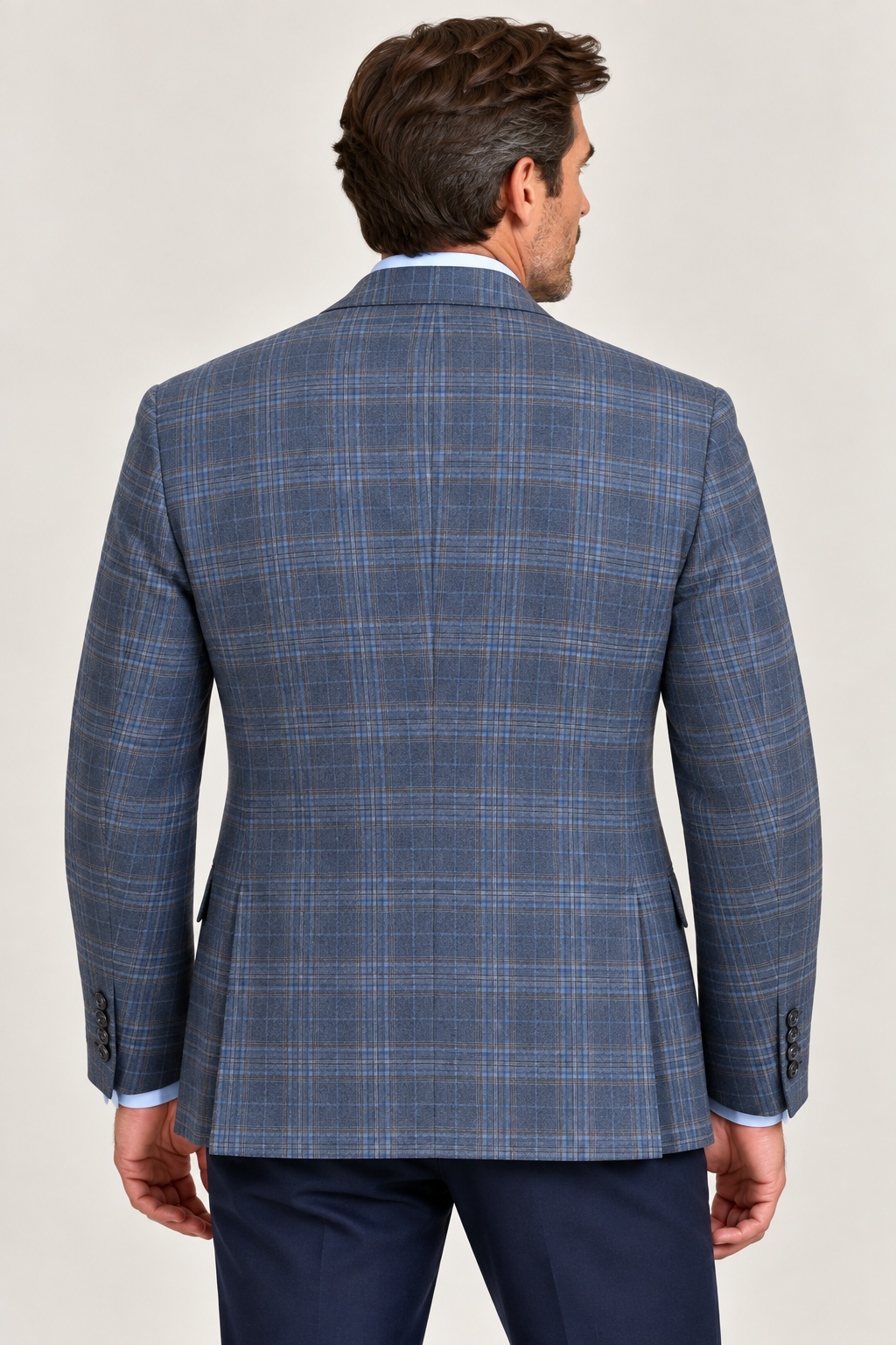 A man is seen from behind wearing the TailoRed Giacomo Plaid Sport Coat 8110669 in navy, crafted from Italian wool by TailoRed, paired with a light blue dress shirt and dark pants, set against a plain light background.