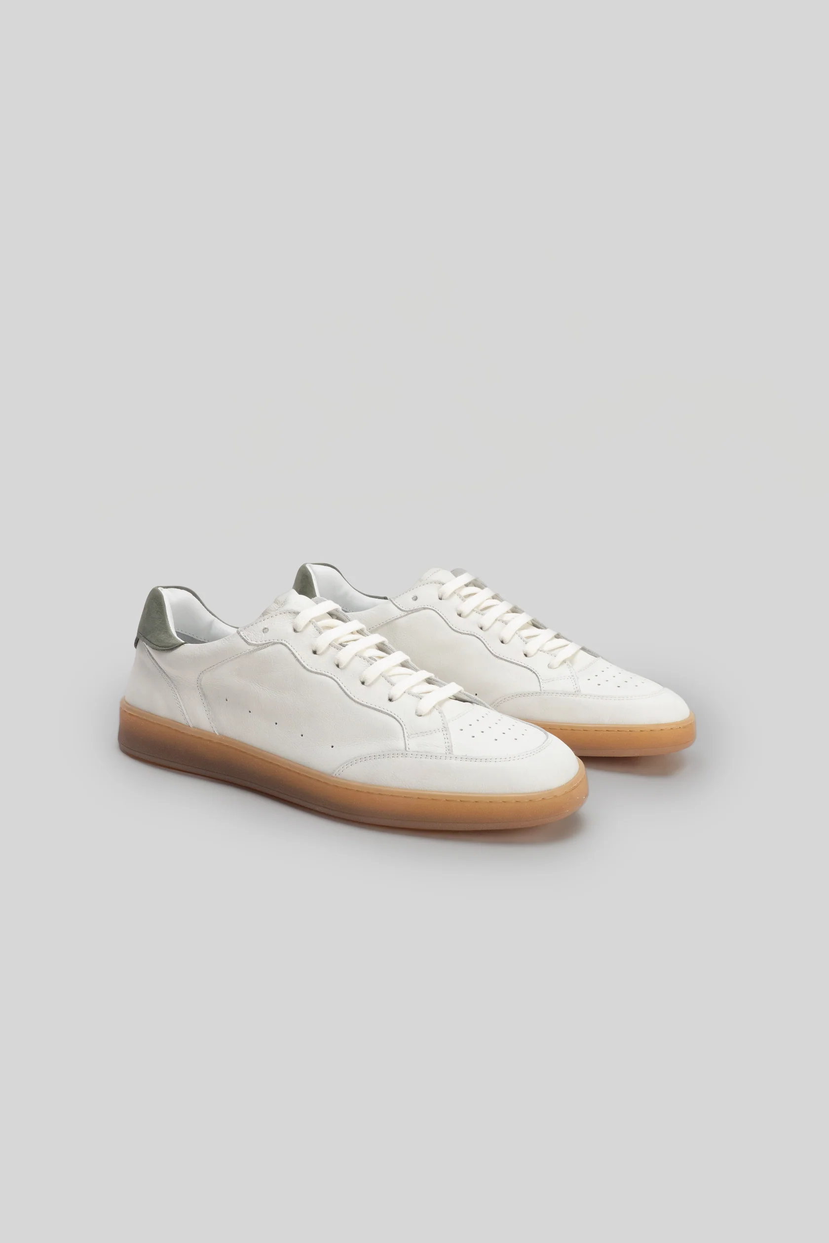 The Robert Barakett Rodney Court Sneaker by Robert Barakett is a white low-top calfskin sneaker featuring tan rubber soles and light gray heel accents, showcased against a plain light background.