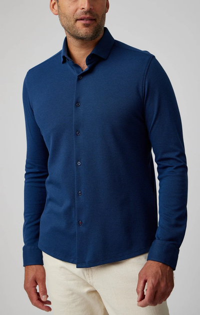 A man wearing a Stone Rose ORIGIN - Long Sleeve T-Series Sport Shirt and light-colored pants stands against a plain background.