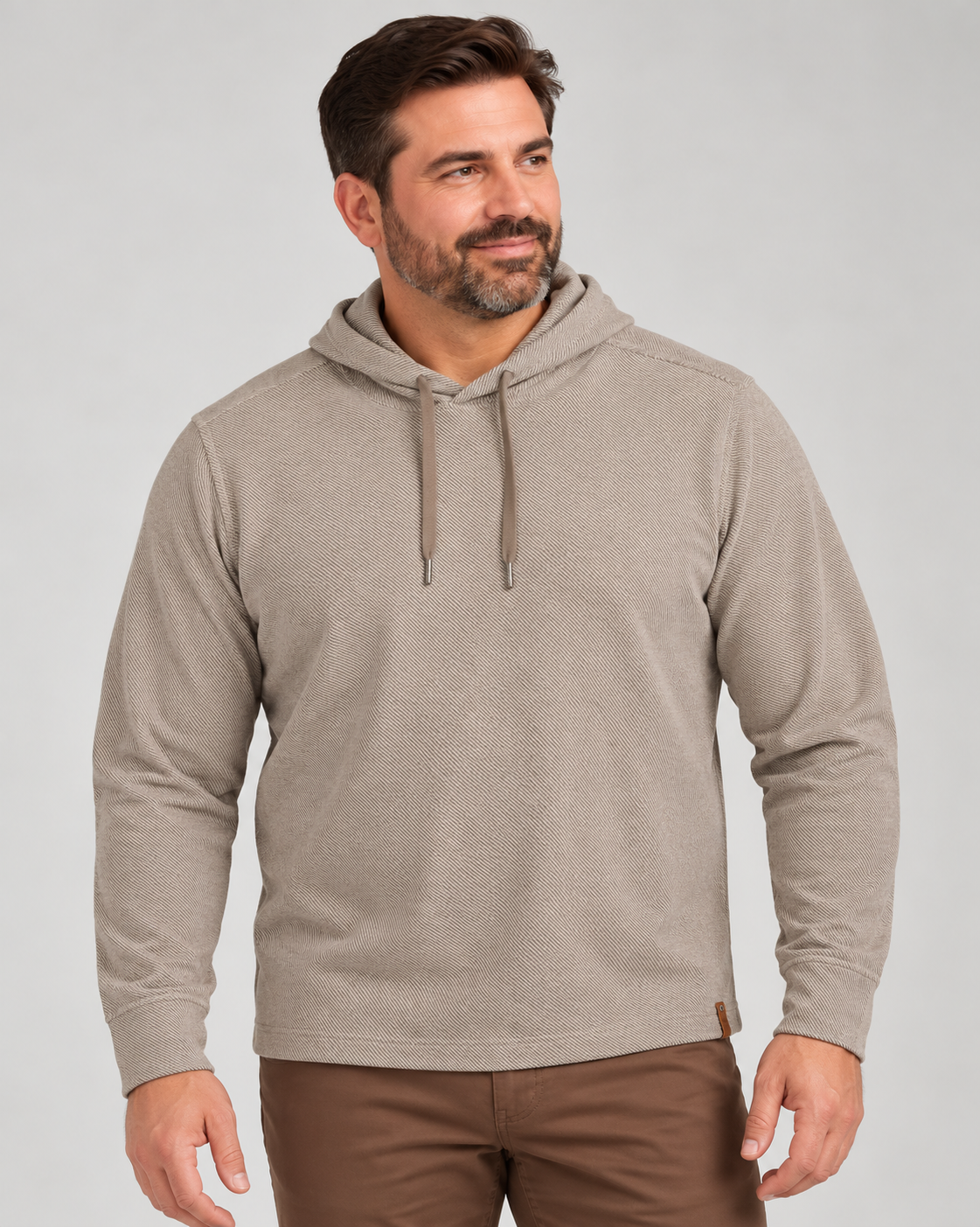 A man wearing a tan Tommy Bahama Fireside Coast Hoodie Big & Tall with a drawstring and brown pants.