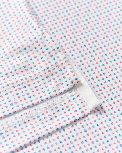 Close-up of the Johnnie-O Big & Tall Performance Jersey Polo - Glidey, featuring white fabric with a red and blue geometric print, plus detailed stitching for a sporty golf polo look.