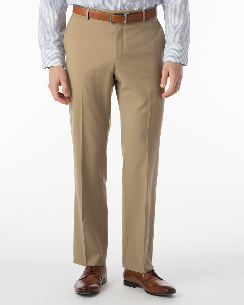 A person wearing Ballin Super 120's Comfort-EZE Big & Tall dress pants in British Tan, a light blue dress shirt, a brown belt, and brown dress shoes stands against a plain white background.