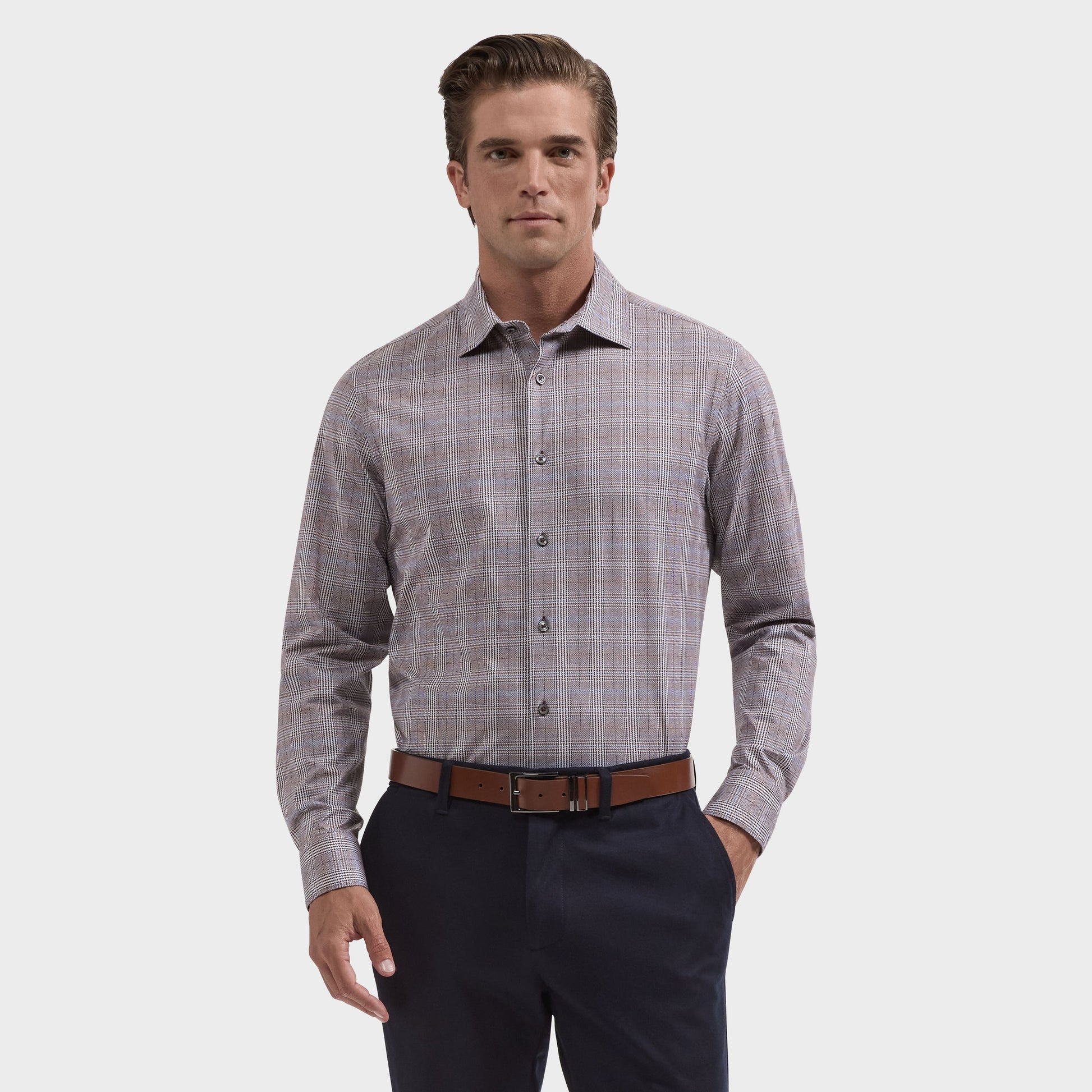 A man wearing the Bugatchi James Plaid Sport Shirt (KF9278K60), a long-sleeve, wrinkle-resistant shirt by Bugatchi, tucked into dark pants with a brown belt, stands against a plain white background.