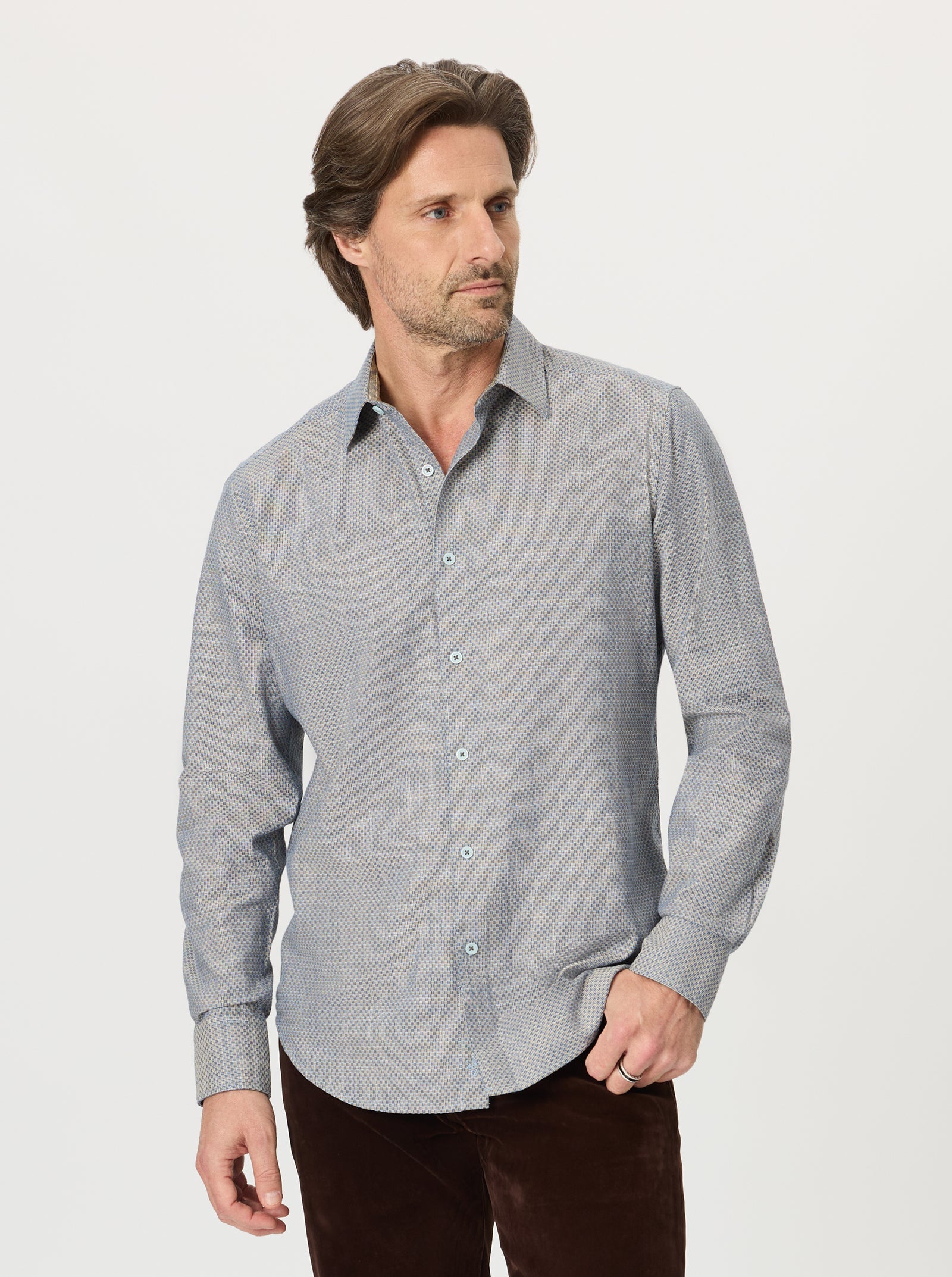 A man wearing the Robert Graham Grandadam Woven Shirt Big & Tall in a patterned light blue stands facing left with one hand in his pocket, paired with dark pants, against a plain white background.