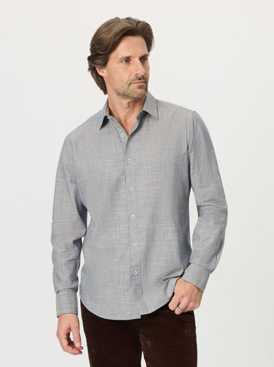 A man wearing the Robert Graham Grandadam Woven Shirt Big & Tall in a patterned light blue stands facing left with one hand in his pocket, paired with dark pants, against a plain white background.