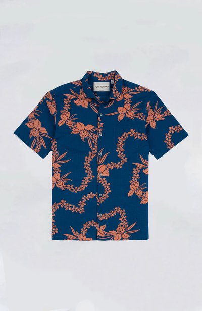 The Tori Richard Lei Hawaiian Shirt by Tori Richard features a navy base with an orange floral and vine pattern, a cutaway collar, and short sleeves. Made in Hawai'i, it is displayed against a plain light background.
