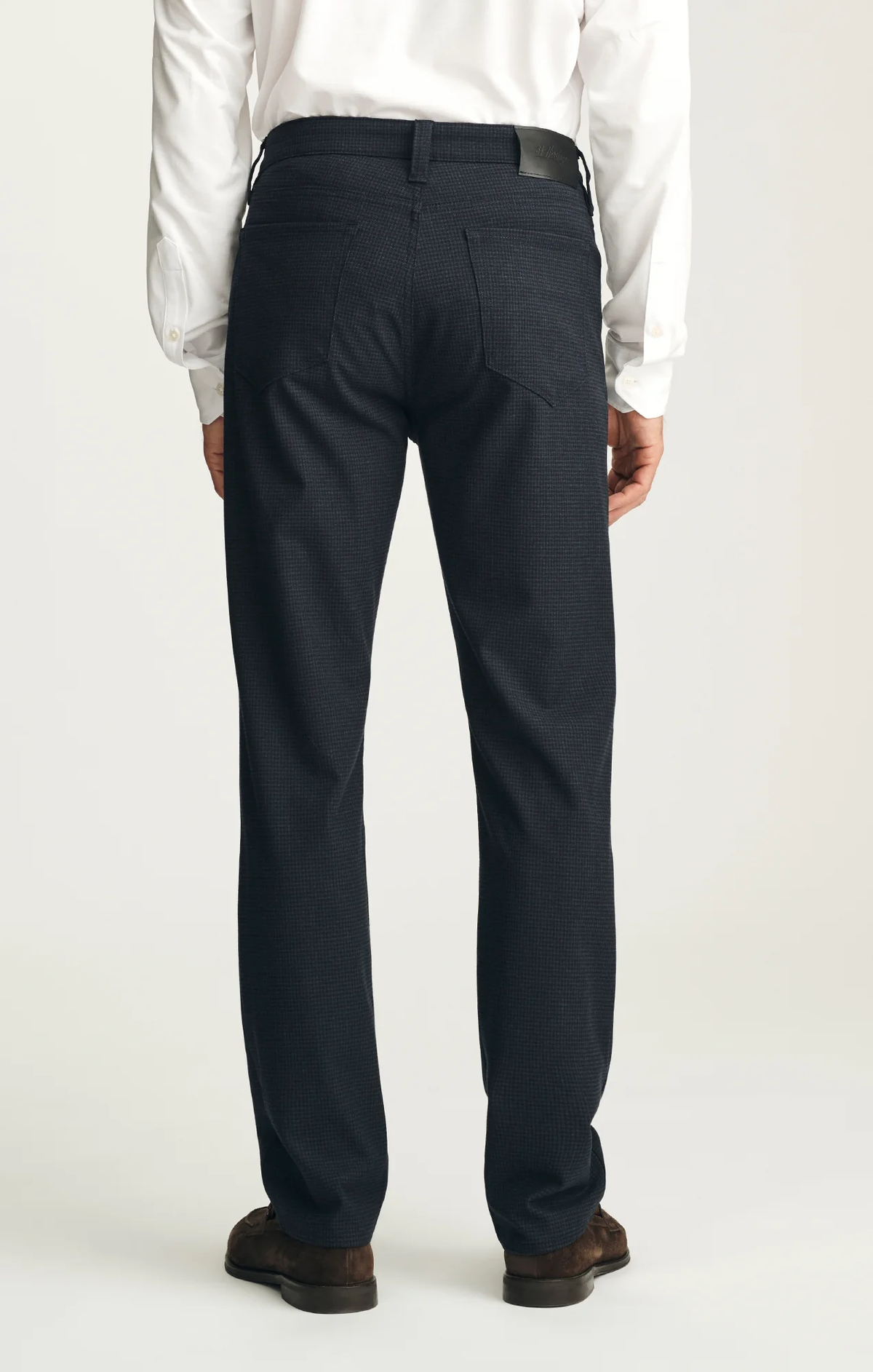 A person is shown from the back, wearing the 34 Heritage Courage Supreme Plaid trousers by 34 Heritage, paired with a white dress shirt and brown shoes, standing against a plain light background.