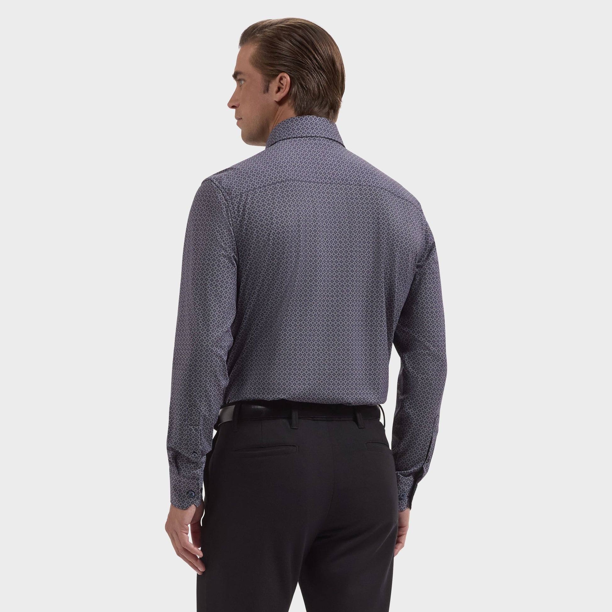 A man stands with his back to the camera, wearing the Bugatchi Devon Medallion Sport Shirt (KF9433K80) and black pants against a plain white background.