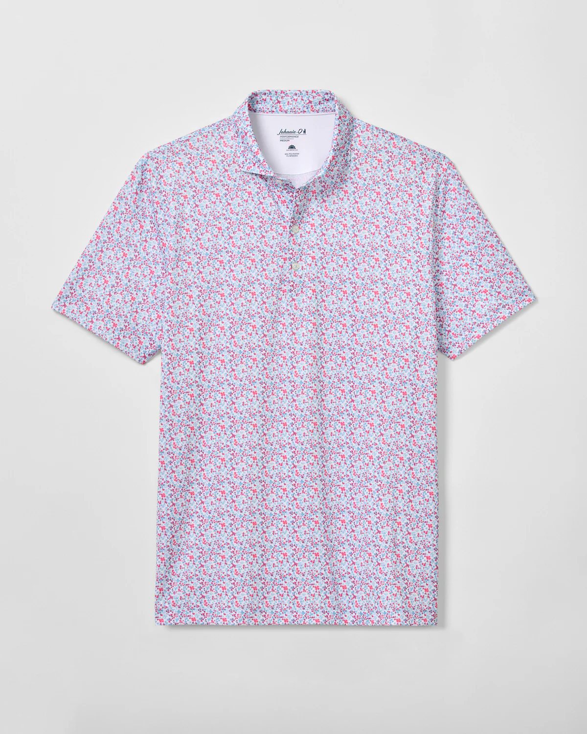 The Johnnie-O Charmer Jersey Polo by Johnnie-O is a short-sleeve collared performance jersey polo with a pink, blue, and white floral print, shown on a light gray background.