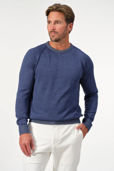 A man stands against a plain white background with his left hand in his pocket, wearing the Garnet Crew Valmont Sweater 2522001CS by Garnet and white pants.