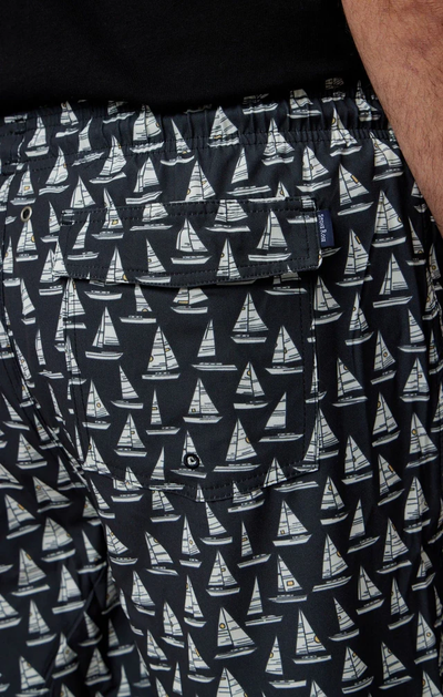 Close-up of Stone Rose HELIOS - Black Sailboats Swim Shorts, featuring an all-over white sailboat print, back pocket with button, and a small navy tag.