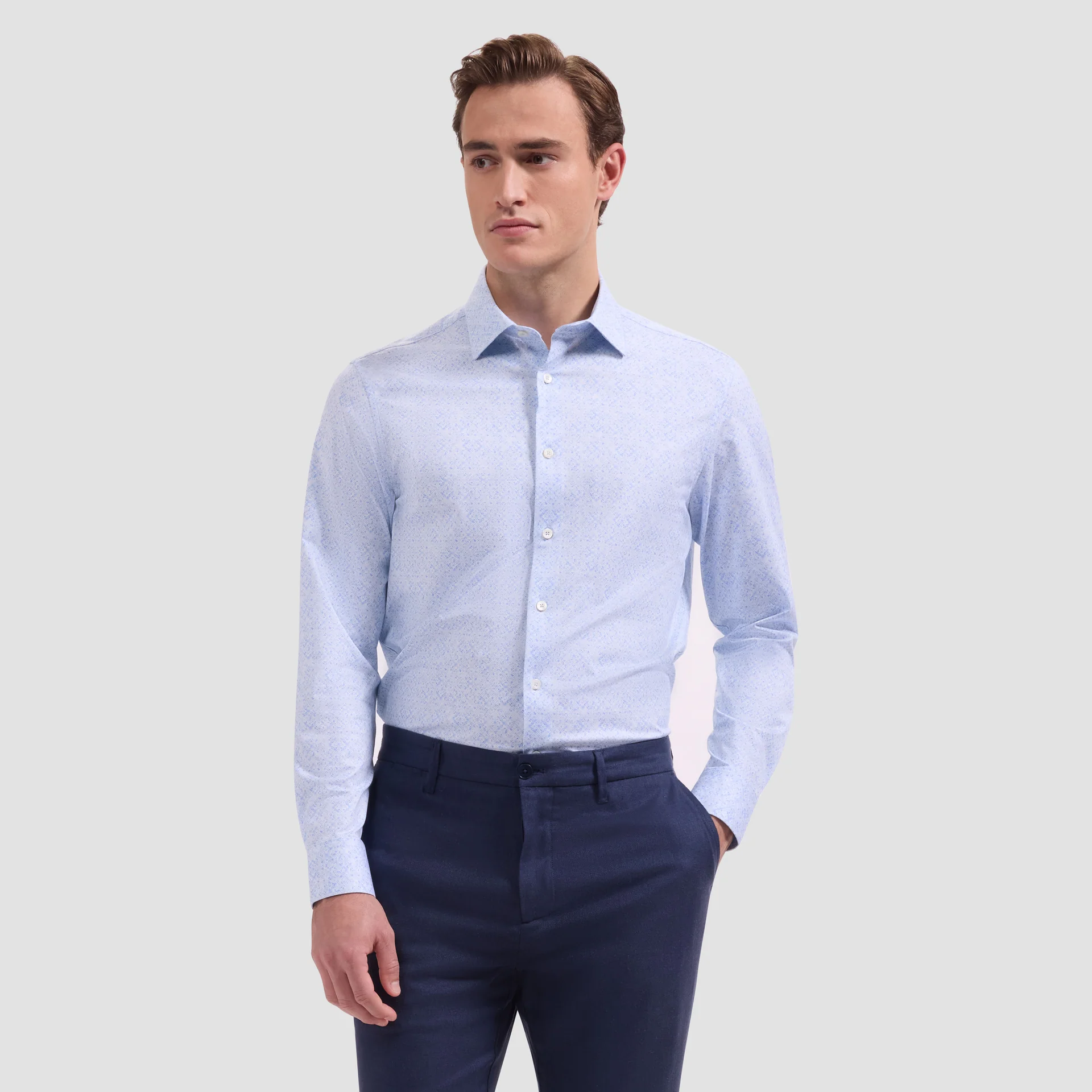 A man wearing a Bugatchi OP Jimmy OoohCotton® Floral Shirt JF9635K61 and dark blue trousers, standing against a plain light gray background.