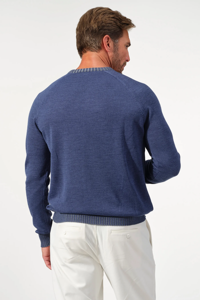 A man stands facing away, wearing the Garnet Crew Valmont Sweater 2522001CS by Garnet in blue with white pants against a plain light background.