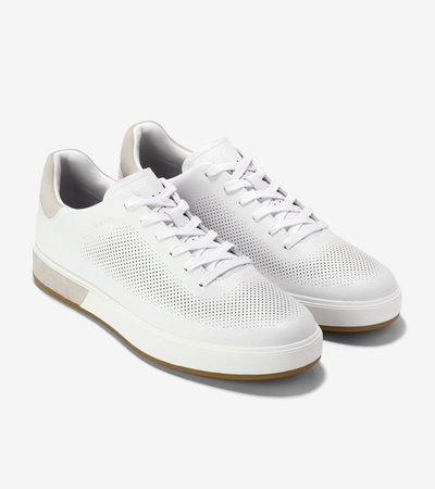 The Cole Haan GrandPro Angleace Sneakers by Cole Haan feature a leather upper, white laces, beige heel accents, perforated sides, and light brown rubber soles, shown on a white background.