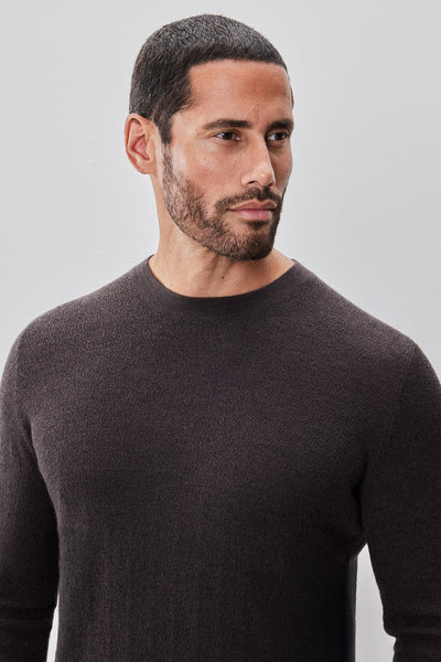 Man with short black hair and a trimmed beard wearing the Robert Barakett Watertown Sweater by Robert Barakett, looking slightly to the side against a plain light background.