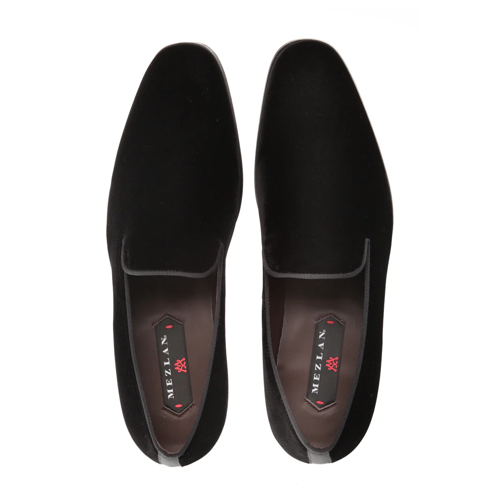 The Mezlan Lublin Velvet Loafer is a black men's slip-on dress shoe made of velvet, handmade in Spain, with Mezlan branding on the insole and shown from an overhead view.