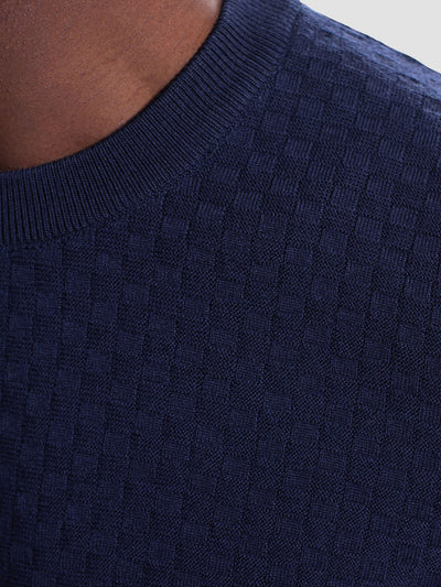 Close-up of a person wearing the Bugatchi Basketweave Crew Neck Sweater HH202CN1, a navy blue merino wool sweater with textured knit and ribbed neckline by Bugatchi.