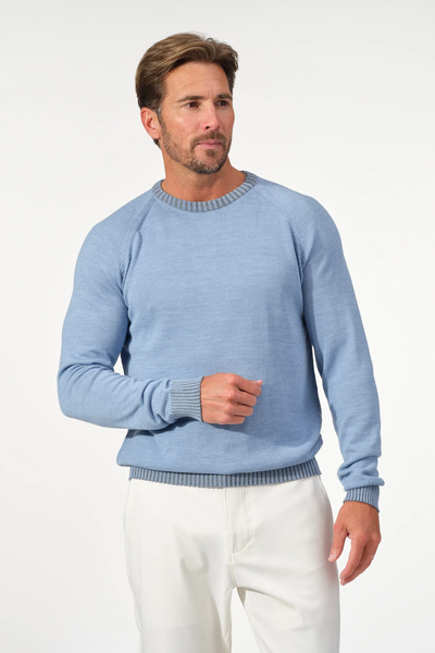 A man wearing the Garnet Crew Valmont Sweater 2522001CS by Garnet in light blue and white pants stands against a plain white background.