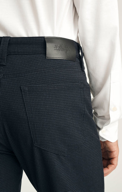 Close-up of a person wearing the 34 Heritage Courage Supreme Plaid pants and a white shirt, showing the back pocket and a black leather 34 Heritage brand patch on the waistband.