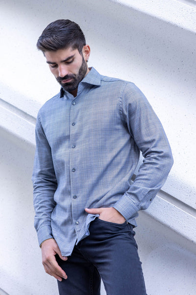 A man with a beard, wearing the Garnet Roll Up Collar Shirt Big & Tall 2421009 and black jeans, stands against a white textured wall, looking downward with one hand in his pocket.