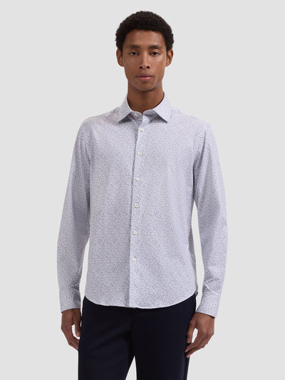 A man wears the Bugatchi OP James OoohCotton® Leaf Print Shirt JF9212K60, a light-colored, long-sleeve shirt with a subtle leaf print by Bugatchi, paired with dark pants against a plain light gray background.