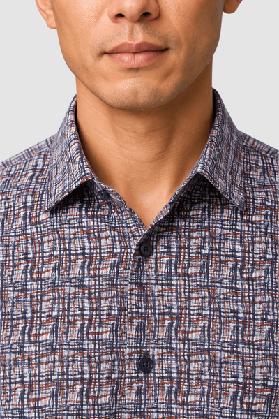 A close-up of a person wearing the Garnet Vincent Tile Print Sport Shirt 2621032, featuring a blue and brown abstract pattern. Only the lower face and upper torso are visible.