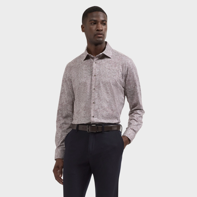 A man stands against a plain background wearing the Bugatchi James Abstract Sport Shirt KF9300K60, paired with dark trousers and a black belt.