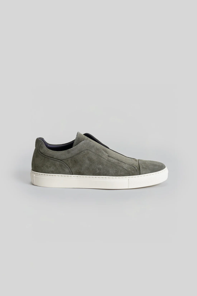 The Robert Barakett Catro Suede Sneaker, by Robert Barakett, is a grey Italian suede slip-on with a white sole and cushioned insole, shown in side profile against a plain light grey background.