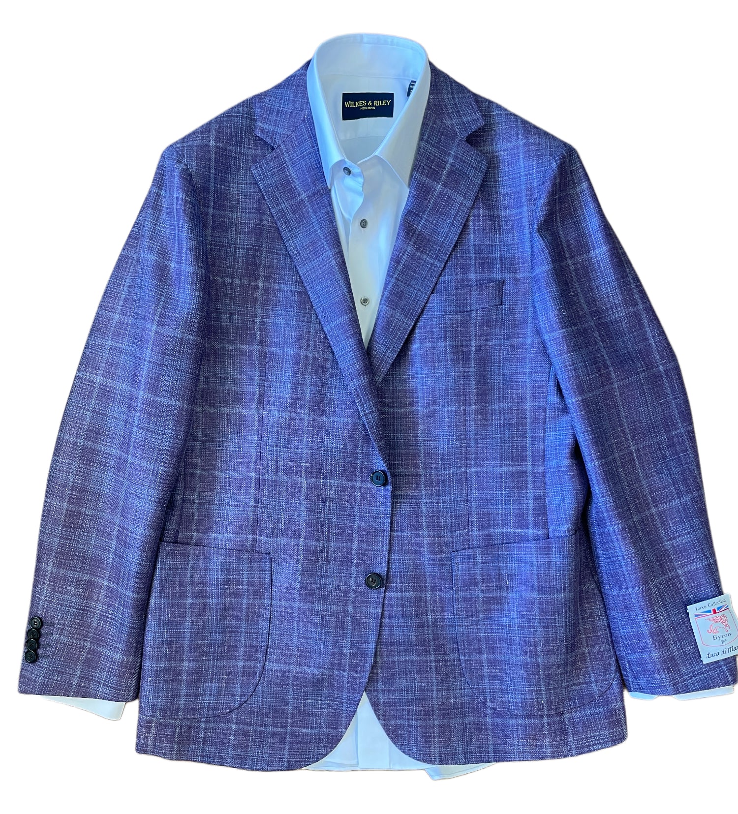 The Byron Luca Soft Sport Coat 9547 by Byron features a purple plaid design, two front pockets, black buttons, and is styled with a light blue dress shirt underneath, shown on a white background for a modern blazer look.