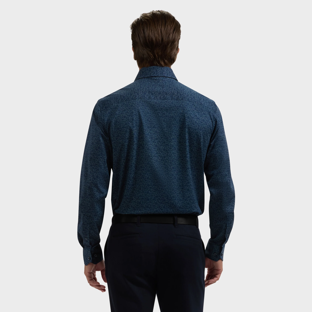 Man facing away, wearing a long-sleeved Bugatchi James Floral Sport Shirt in dark blue and black pants, shown from the back against a plain light background.
