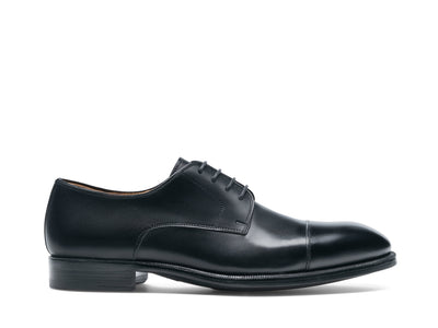 The Magnanni Harlan by Magnanni is a black leather smart-casual derby shoe with a cap toe, low heel, and smooth finish, displayed in side profile on a white background.