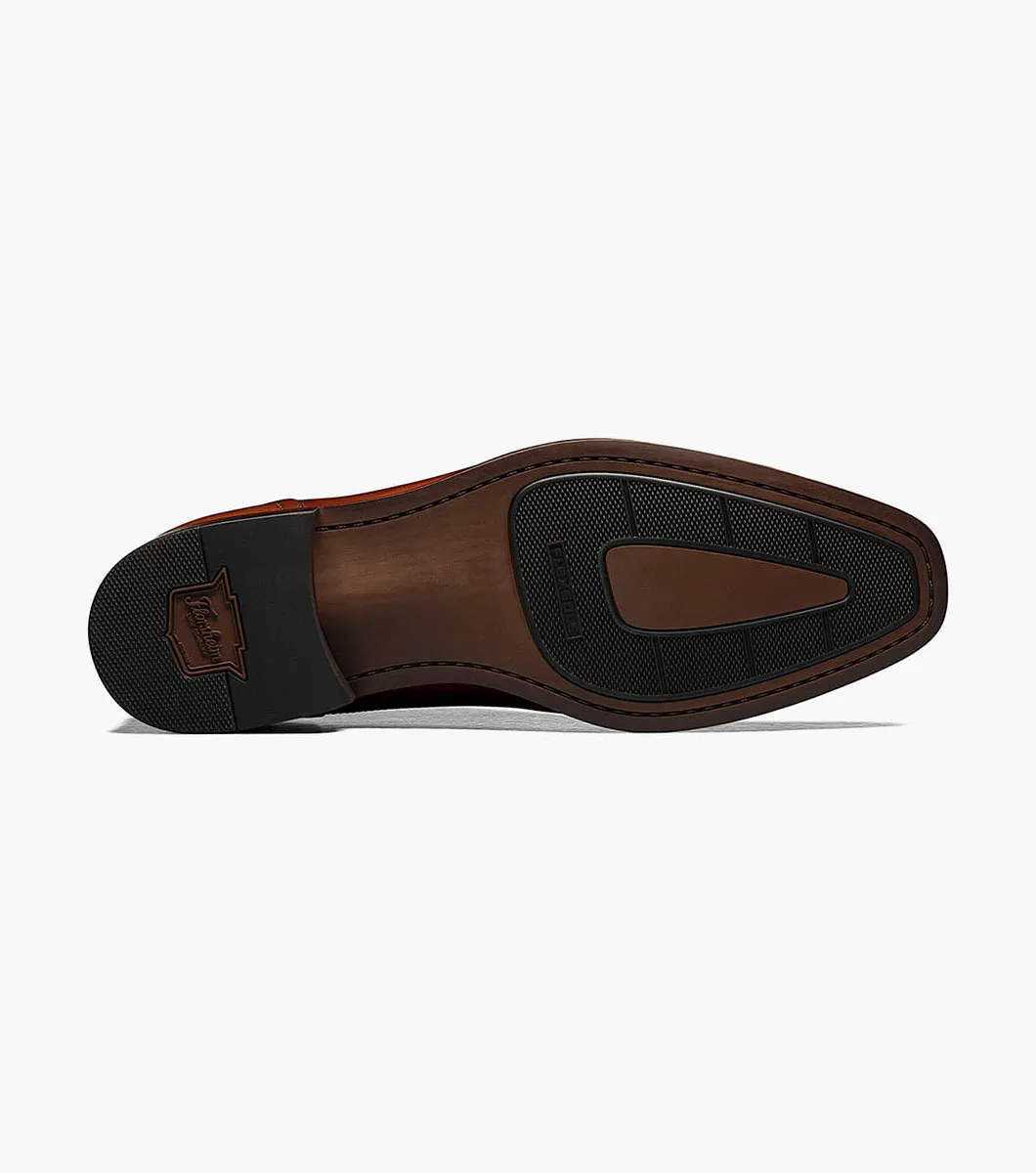 The image displays the sole of the Florsheim Sorrento Cap Toe Oxford, a brown leather dress shoe by Florsheim, which features black rubber grip sections and a rectangular logo on the heel. This sophisticated design is finished with a cushioned footbed, offering both style and comfort for all-day wear.