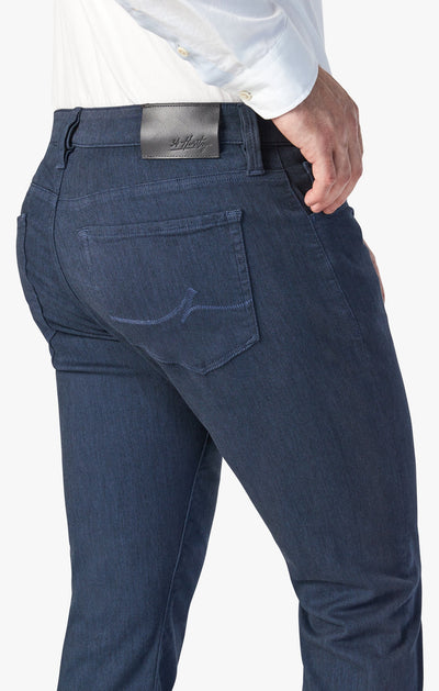 A person wears 34 Heritage Charisma Diagonal Big&Tall relaxed straight leg trousers in dark blue by 34 Heritage, paired with a white shirt, shown from the waist down with one hand on their hip.