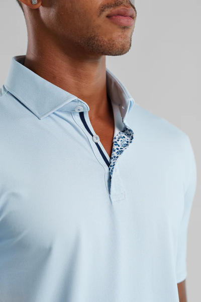 Man wearing the Stone Rose Apex Birdseye Polo BSCSSP51 in light blue, with a floral pattern inside the collar and placket—perfect for summer style. Shown from the shoulders up.