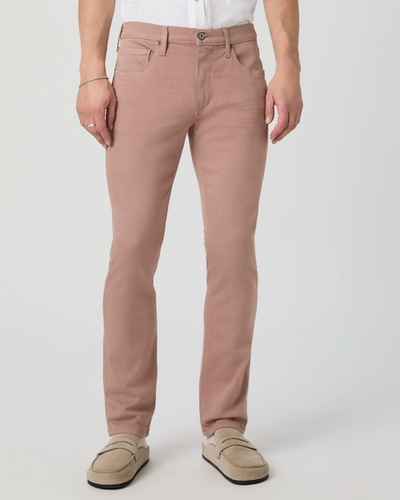 A person wearing Paige Federal Slim Straight Jeans in light pink, a white shirt, and beige loafers stands against a plain light background.