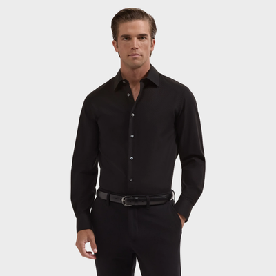 A man stands against a plain background wearing a wrinkle-resistant black Bugatchi Julian Tonal Geometric Jacquard Shirt, paired with black pants and a black belt.