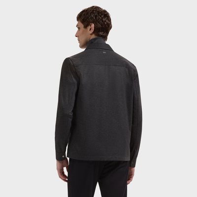 A man stands facing away, wearing the Bugatchi Micro Check Knit Shirt KF2313K93—crafted from performance stretch fabric—paired with black pants, set against a plain light gray background.