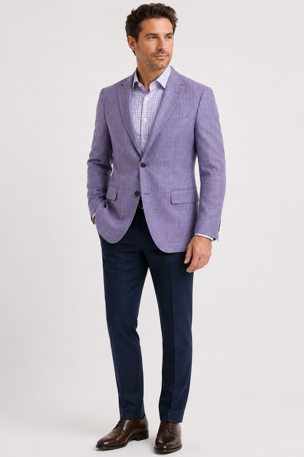 A man stands against a plain background wearing the Paul Betenly Kevin Purple Sport Coat 2K6103, crafted from luxurious Super 120’s wool, paired with a light checked shirt, dark blue trousers, and brown dress shoes.