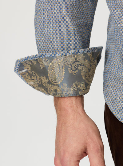A person wearing the Robert Graham Grandadam Woven Shirt Big & Tall by Robert Graham, featuring a blue cotton micro-check pattern with rolled-up sleeves that reveal a paisley-patterned inner cuff.