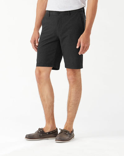 A man wearing Tommy Bahama Chip Shot Shorts Big & Tall by Tommy Bahama, a light t-shirt, and brown boat shoes stands against a plain white background.