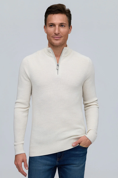 A man wears the Raffi Merino Zip Mock HWC12948-Z sweater in cream, featuring an English Rib knit, paired with blue jeans, standing against a plain light gray background.