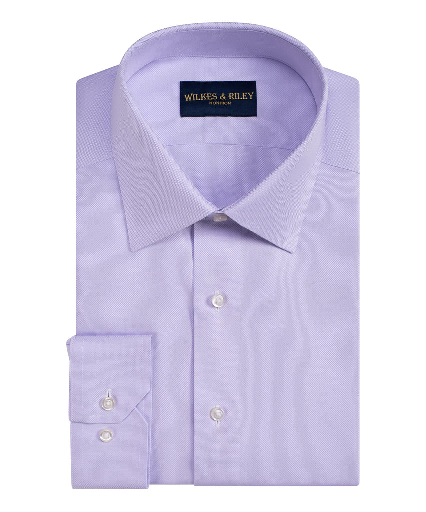 A neatly folded light purple WilkesRiley Queens Oxf Classic dress shirt in Supima cotton, with a pointed collar and buttoned cuffs, featuring the Wilkes & Riley brand label inside the collar.